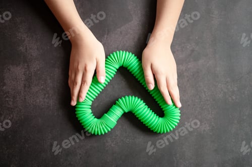 Preview: anti stress sensory pop tube toys in a kids hands. kids hands plays with poptube toy on black table