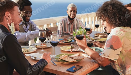 Preview: Happy multiracial people enjoy dinner together outdoor on partio