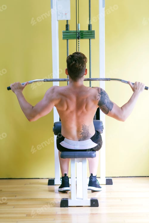 Preview: Fit man on lat pull down machine at the health club. Work out on Pull down Weight Machine