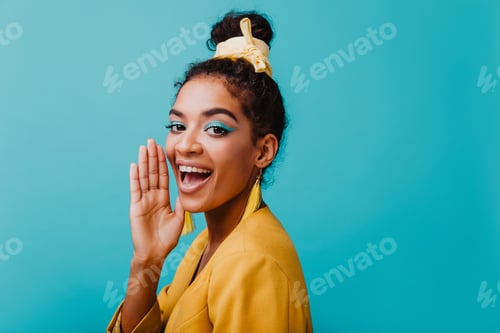 Preview: Refined black girl wears yellow earrings chilling during photoshoot. Studio portrait of joyful afri