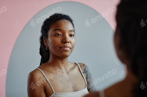 Preview: Young black woman looking in mirror smiling