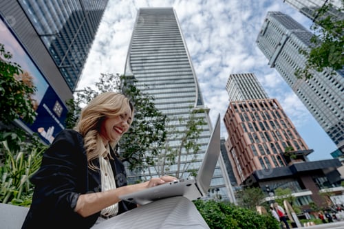Preview: Professional woman working on her laptop in a dynamic cityscape