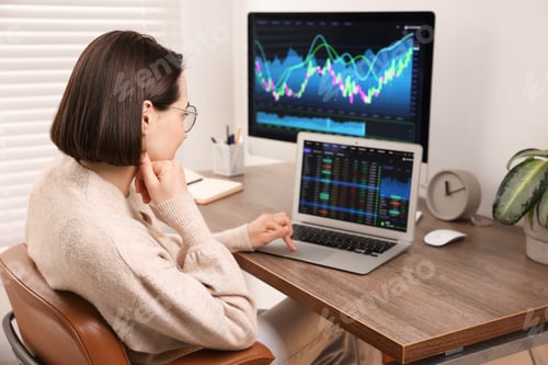 Preview: Stock exchange. Woman analysing financial market on laptop at wooden table indoors