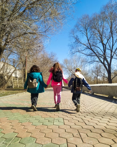 Preview: children with backpacks walk hand in hand on a sunny day. Back to school.