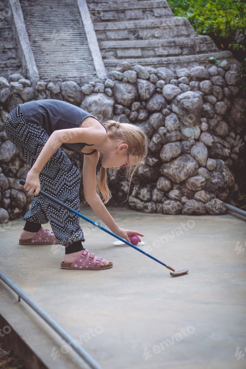 Preview: Happy little girl playing mini golf.