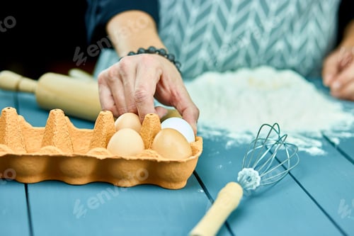 Preview: Close up of male hands breaking raw egg over flour.