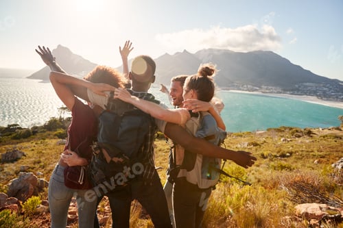 Preview: Young adult friends on a hike celebrate reaching a summit near the coast together