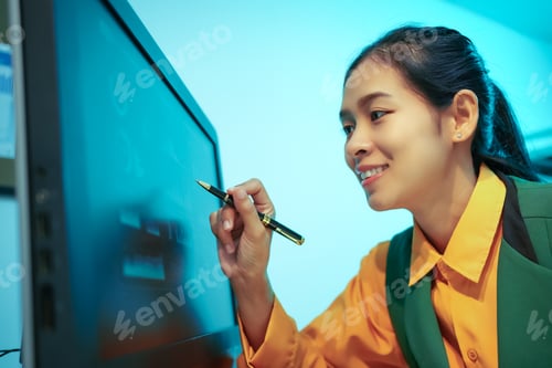 Preview: An Asian businesswoman analyzes digital charts on a computer screen, reviewing performance reports