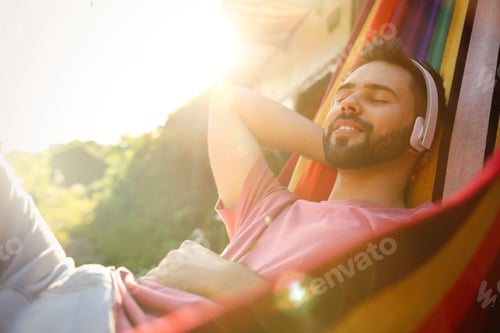 Preview: Young man listening to music in hammock near motorhome outdoors on sunny day