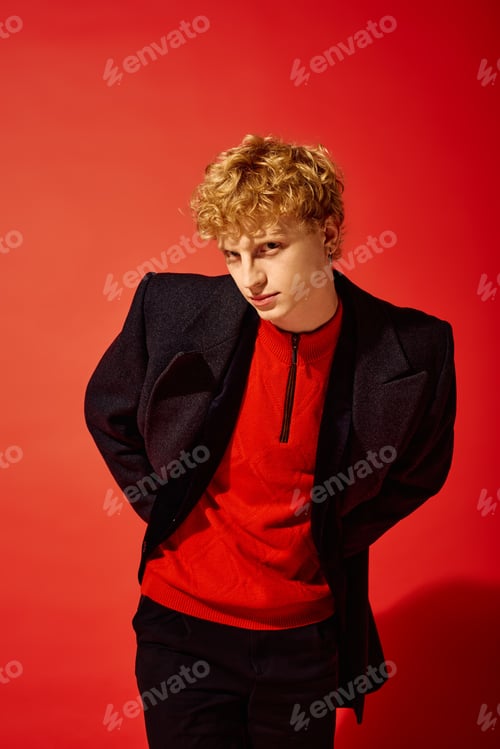 Preview: Fashion forward man showcases holiday style against a vibrant red backdrop