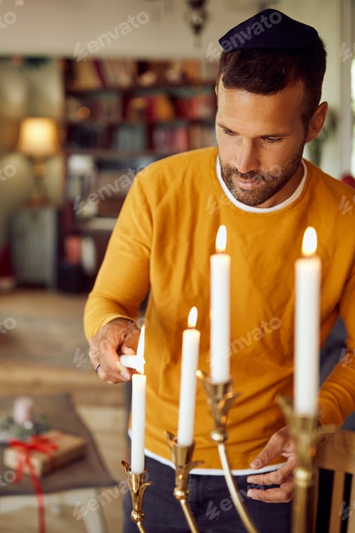 Preview: Jewish man lighting up traditional Hanukkah candles at home.