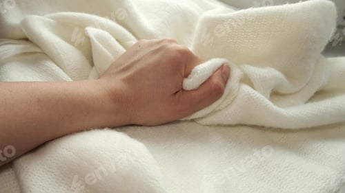 Preview: female's hand on the fabric of white plush cloth with soft nap. Clothing industry concept, slow