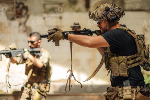 Preview: Group of air soft players aiming with rifles at opponent in ruins.