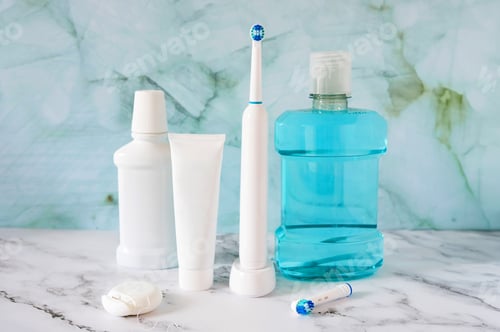 Preview: Essential oral hygiene products: electric toothbrush, floss, toothpaste tube and mouthwash.