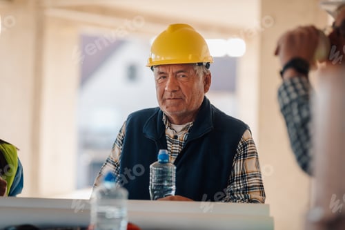 Preview: Senior construction worker taking break with colleagues on building site