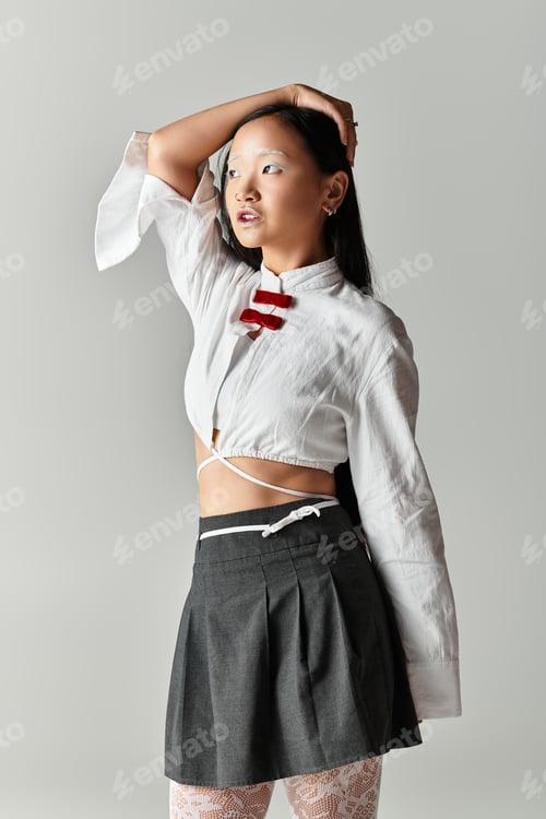 Preview: Stylish young woman with blue hair poses confidently in a grey studio setting