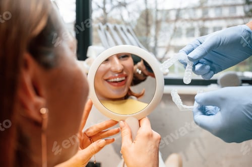 Preview: Using mirror to look at aligner on teeth. Woman in the stomatology clinic, visiting dentist