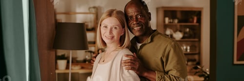 Preview: Senior Caucasian Woman and Senior Black Man Embracing and Smiling Indoors