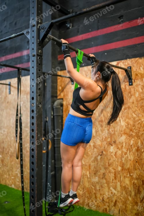 Preview: Woman exercising with elastic band in a gym