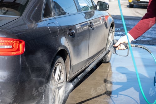 Preview: A man washes off the foam while washing the car.