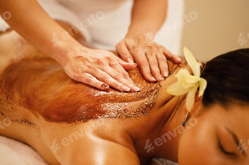 Preview: Close-up of therapist massaging woman's back with hot chocolate.