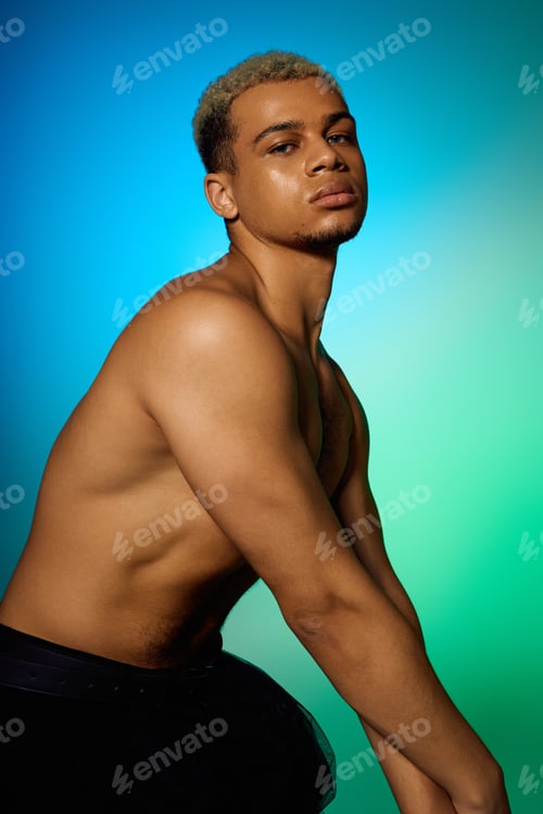Preview: Muscular young man displays confidence in vibrant studio light