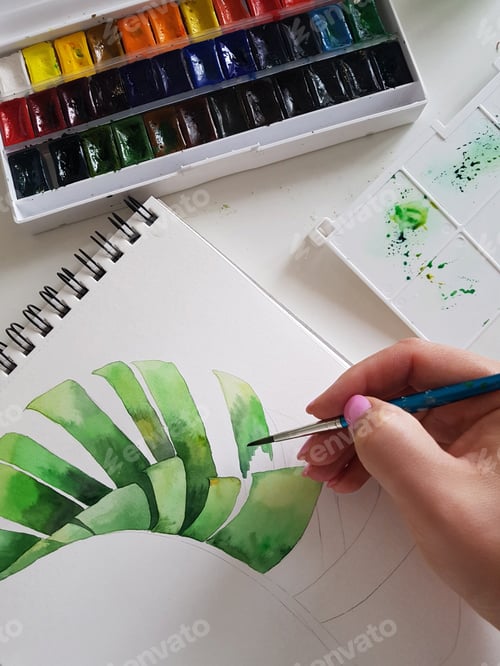 Preview: Woman painting banana leaf with watercolors close up