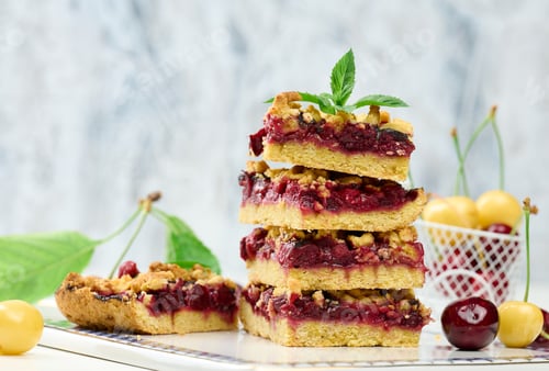Preview: Square slices of cherry crumble lie in a stack on a white board