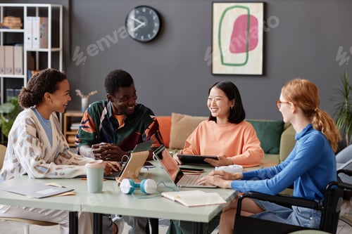 Preview: Diverse group of young people laughing happily during meeting in IT office