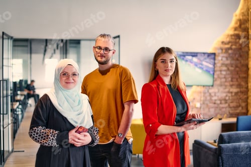 Preview: A group of young business colleagues, including a woman in a hijab, stands united in the modern