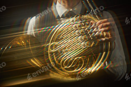 Preview: Person Playing Golden French Horn Shining in Bright Spotlight on Stage