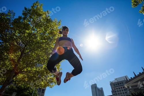 Preview: Low angle view of athletic woman jumping in the air in the city