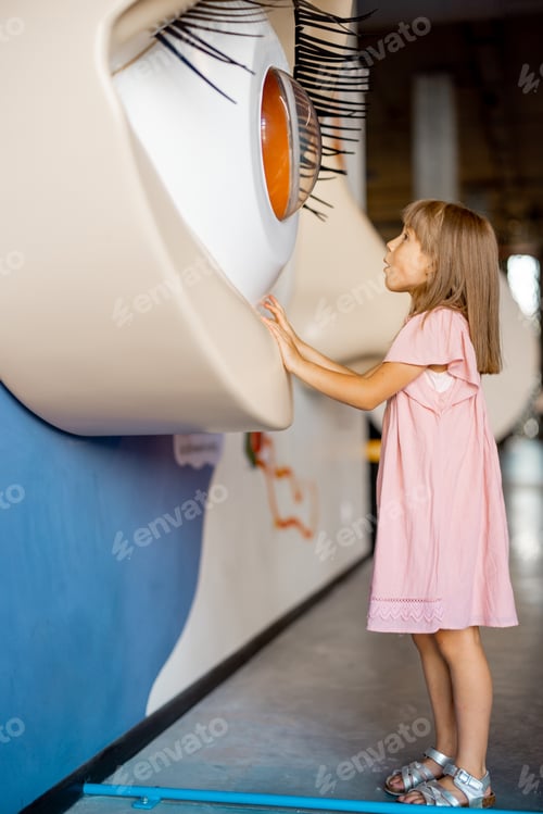 Preview: Little girl looks on a big eye model