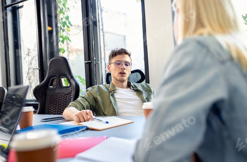 Preview: Two young business people working on new project together in office.