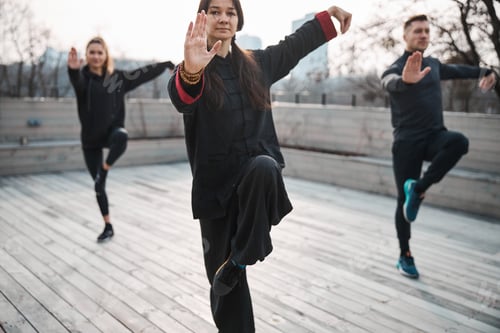 Preview: Woman master of tai chi holding balance with two people