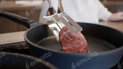 Preview: Close up of woman female cook putting ribeye on frying pan with non stick coating. Action. Preparing