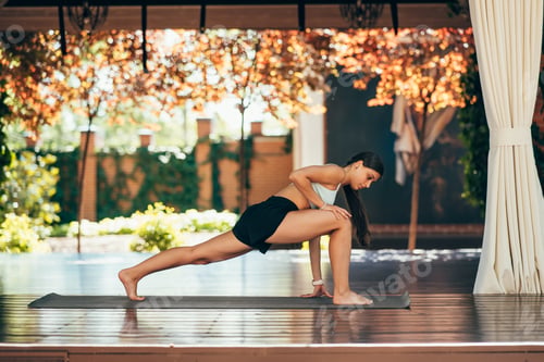 Preview: Young woman performs virabhadrasana. Practicing yoga alone