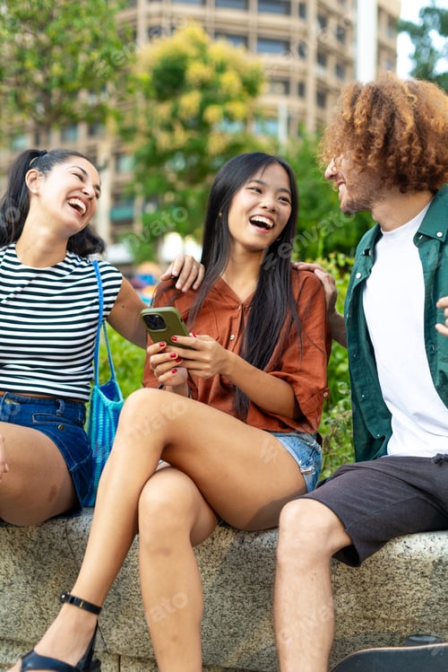 Preview: Happy multi ethnic friends laughing together using a smartphone outdoors