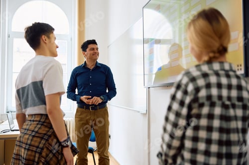 Preview: Happy teacher and his students using interactive whiteboard during a class at high school.