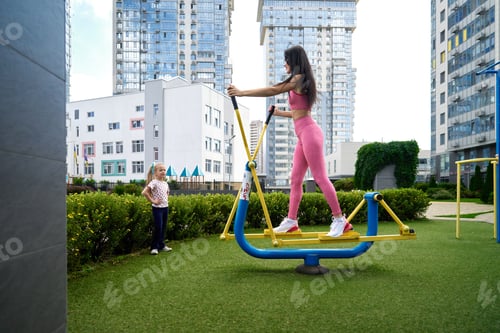 Preview: Mother and daughter are exercising in a city park on a sunny day.