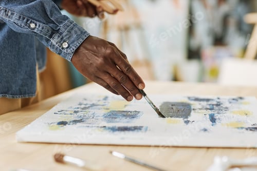 Preview: Selective focus on hand of young black man painting with acrylic paints