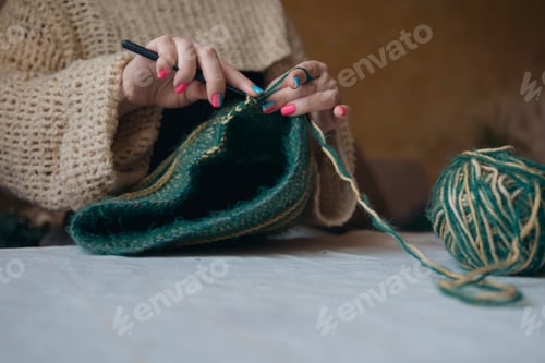 Preview: Female hands holding crochet hook, working on green and yellow hat