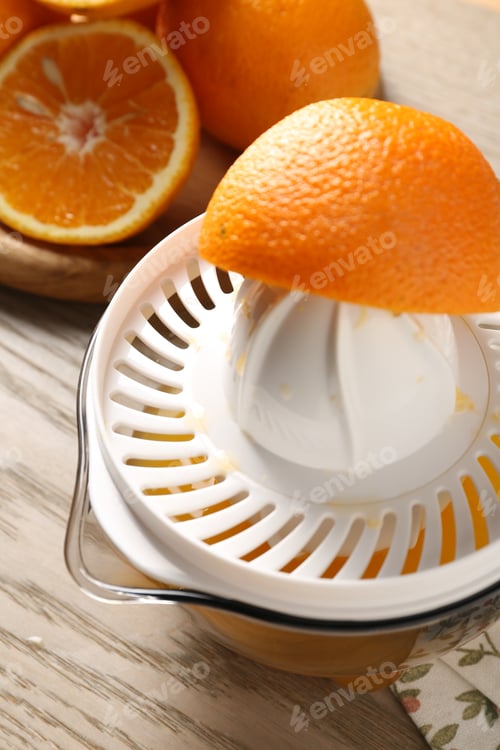 Preview: Making juice. Juicer and fresh oranges on wooden table, closeup