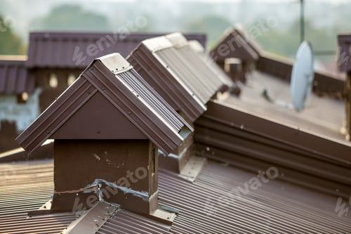 Preview: Close-up detail of new built brick plastered chimneys on house top with metal tile roof. Roofing
