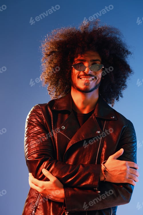 Preview: Portrait of a stylish man with curly hair on a blue background multinational, colored light, trendy