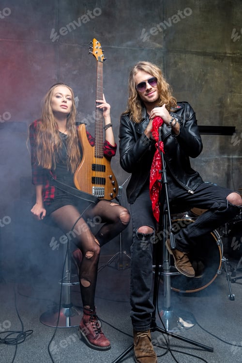 Preview: man with microphone and woman holding guitar in studio, rock and roll band concept