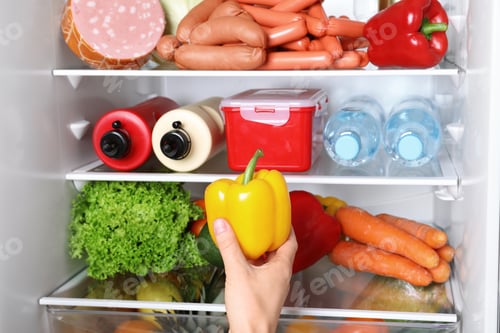 Preview: Woman taking bell pepper from refrigerator, closeup