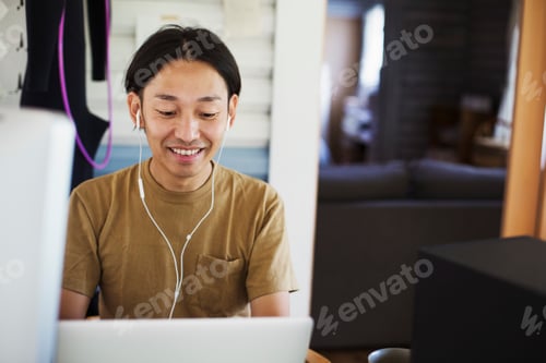 Preview: Smiling man sitting indoors at desk, wearing headphones.