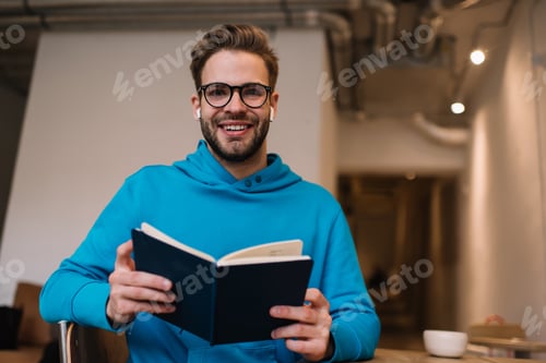 Preview: Happy Caucasian man in bluetooth earbuds listening audio book and posing