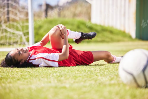Preview: injured, pain or injury of a female soccer player lying on a field holding her knee during a match.